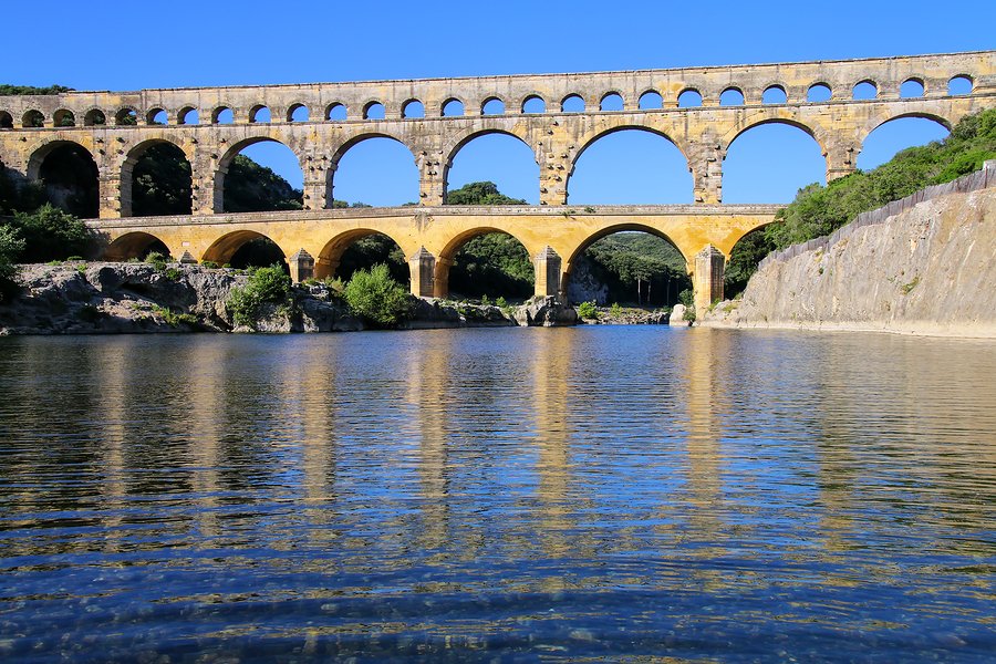 Aqueduct Pont du Gard reflected in Gardon River, southern France. It is the highest of all elevated Roman aqueducts.